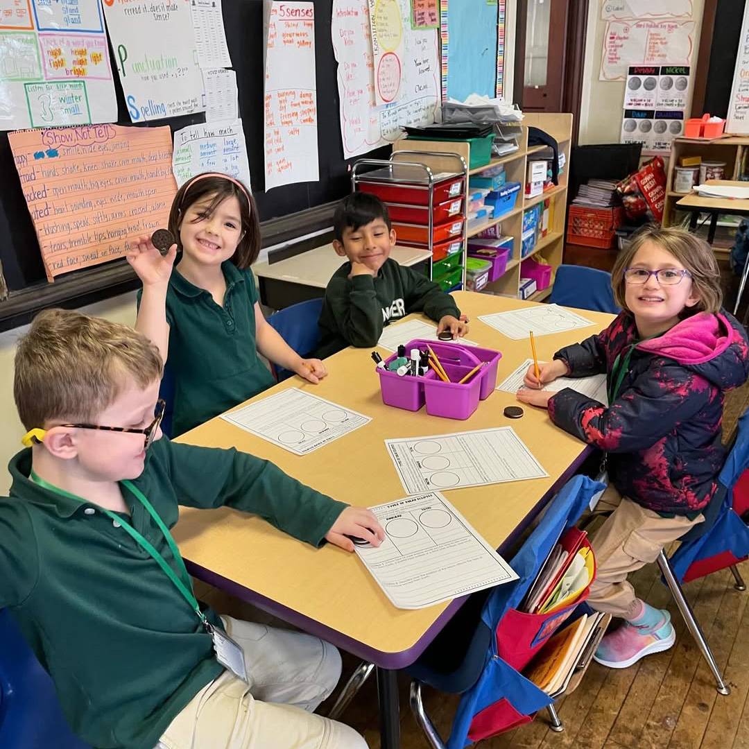 Students Learning Together at Nebinger School Elementary students seated together in a classroom at George W. Nebinger School in Philadelphia working on assignments and participating in a small group learning activity.